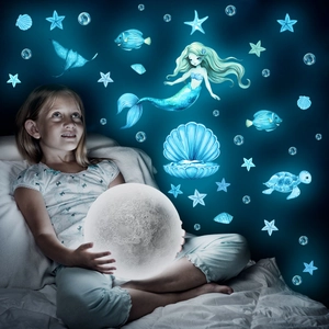 Luminous mermaid ocean wall decals glowing in dark bedroom with blue sea creatures