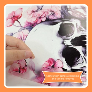 Close-up of hand peeling a floral skull Halloween sticker showing the adhesive backing