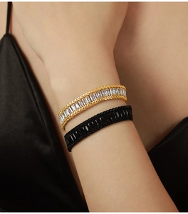 Dettaglio ravvicinato di bracciali hip-hop intrecciati oro e nero con zirconi incastonati