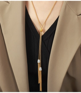 Detail van een lange gouden kwastjesketting met zirkonia-inleg op een chique hanger