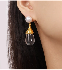 Close-up of elegant gold pear drop earring with round white pearl on female model