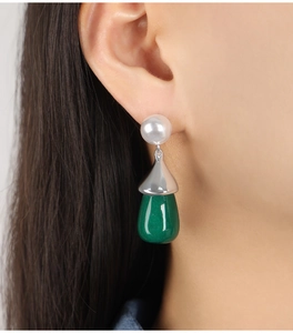 Detailed close-up of pearl and green drop earring worn by a model in soft lighting