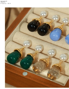 Detail of vintage-style gold earrings with pearls and colorful teardrop pendants