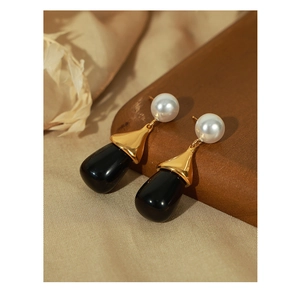 Detail of vintage gold earrings with white pearl and black teardrop resin pendant