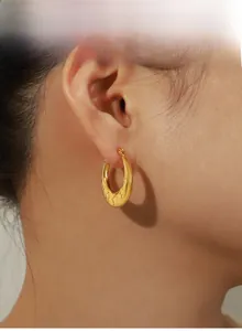 Close-up of vintage gold chunky hoop earrings with engraved stars on a model
