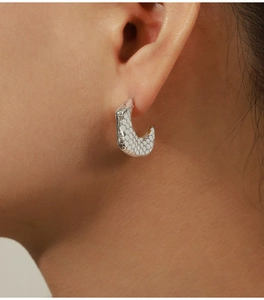 Detail view of silver snake head C-shaped hoop earring with hexagonal scale texture on model