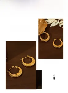 Detail of twisted gold hoop and star-engraved half-moon earrings on vintage tray
