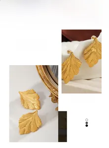 Detailed view of gold leaf earrings showing intricate vein textures and brushed metal finish