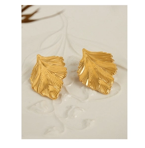 Macro detail of matte gold ginkgo leaf earrings featuring intricate vein textures