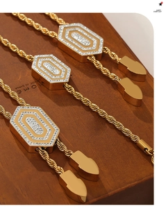 Detailansicht des sechseckigen Zirkon-Anhängers mit goldener Kette auf Holzsockel