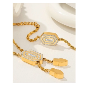 Detail des goldenen Hexagon-Zirkonia-Armbands mit Kordelkette und Patronenanhängern