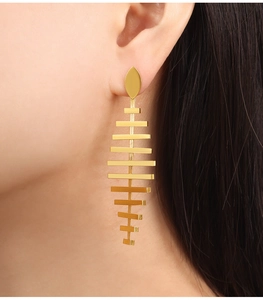 Close-up of golden cascading fishtail fringe earrings with polished geometric tiers