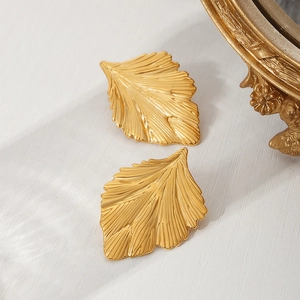 Elegant gold leaf earrings with textured fan-shaped design on a vintage background