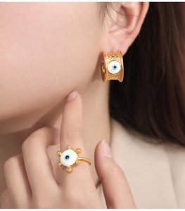 Detail eines goldenen Evil Eye Schmucksets mit gehämmerten Ohrringen und passendem Ring