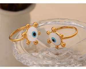 Makroaufnahme von zwei vergoldeten Evil Eye Ringen mit Emaille auf geprägtem Glas