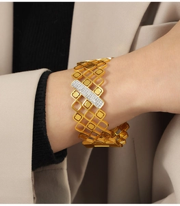 Detalle macro del brazalete dorado geométrico con barra diagonal engastada con diamantes