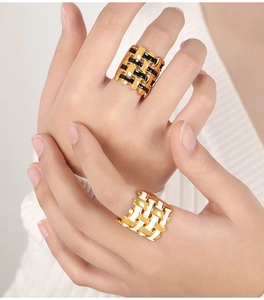 Detail of woven 18k gold plated rings with black and white enamel inlays on fingers