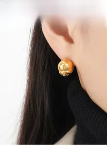 Gros plan d'une boucle d'oreille boule dorée polie avec accents de diamants sur un modèle
