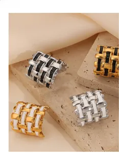 Detailed view of woven texture rings in gold and silver with black and white enamel