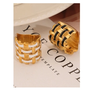Macro detail of gold-plated braided metal rings with black and white enamel inlay