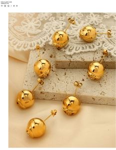 Détail de boucles d'oreilles boules dorées avec strass micro-incrustés sur pierre et dentelle