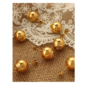 Détail macro de boucles d'oreilles sphériques dorées avec cristal sur fond de dentelle