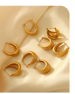 Detail of 18K gold-plated C-shaped earrings with spiral texture on beige silk