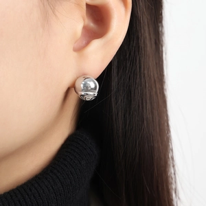 Puce d'oreille sphérique argentée minimaliste avec fini miroir sur l'oreille d'un modèle