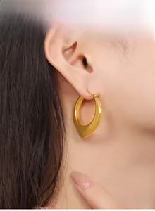 Vue détaillée du modèle portant des boucles d'oreilles créoles dorées en forme de U