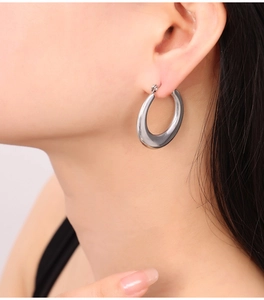 Gros plan d'une boucle d'oreille créole épaisse argentée en forme de U portée par un mannequin