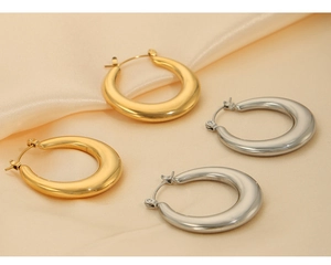 Détail macro de boucles d'oreilles créoles épaisses en U en finitions or et argent poli