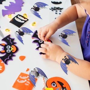 Close-up of child assembling 3D bat wall stickers with googly eyes for Halloween
