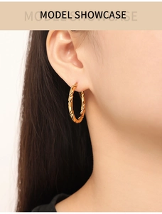 Close-up of golden twisted hoop earrings with a stylish spiral texture on ear