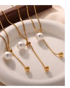 Détail de chaînes serpent dorées avec pendentifs perles blanches et perles réglables