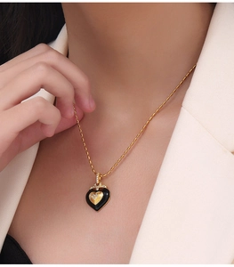 Détail d'un collier en titane doré avec pendentif cœur noir et accents de diamants