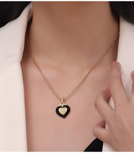 Détail du collier cœur en émail noir et zircons sur une chaîne à perles dorées