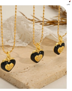 Détail de trois pendentifs coeur en émail noir avec chaîne à perles dorées