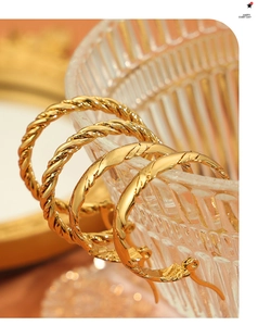 Close-up of four-piece set of gold twisted hoop earrings with textured spiral finish