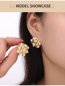 Detail of gold woven earrings featuring multiple white pearls on a model ear