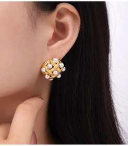 Macro shot of vintage woven gold pearl earrings on a model showing elegant craftsmanship