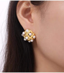 Close-up of vintage braided gold earrings with white pearls worn by a model