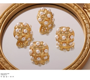Detail of vintage woven gold earrings with pearls on a reflective mirror background