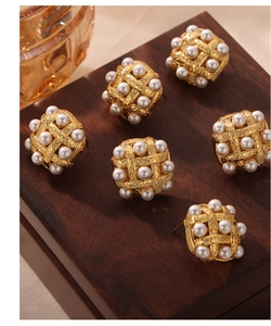 Detailed view of vintage woven gold-plated button earrings with white pearl inlay on wood