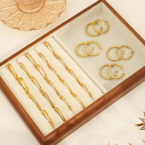 Fashion twisted rope gold hoop earrings in multiple sizes on a gray velvet jewelry tray