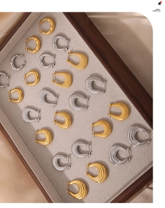 Detalle de pendientes de aro en U de acero de titanio texturizado en color dorado y plateado
