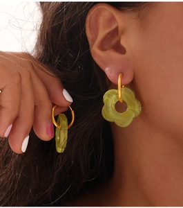 Detailed view of model wearing gold flower earrings with green resin petals and marble texture