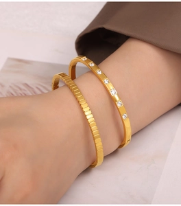 Detail of 18k gold plated stainless steel bangles with textured finish and zircon stones