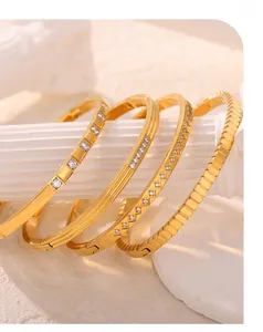 Detail of four luxury gold-plated titanium steel bangles with clear zircon stone inlays