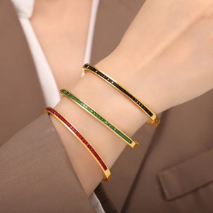 Three gold-plated titanium bracelets with black, green, and red square-cut crystals
