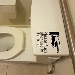 Detail of Please flush text sticker with pointing hand icon on white toilet lid